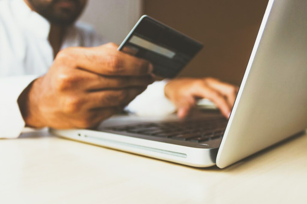 person holding a credit card while using laptop